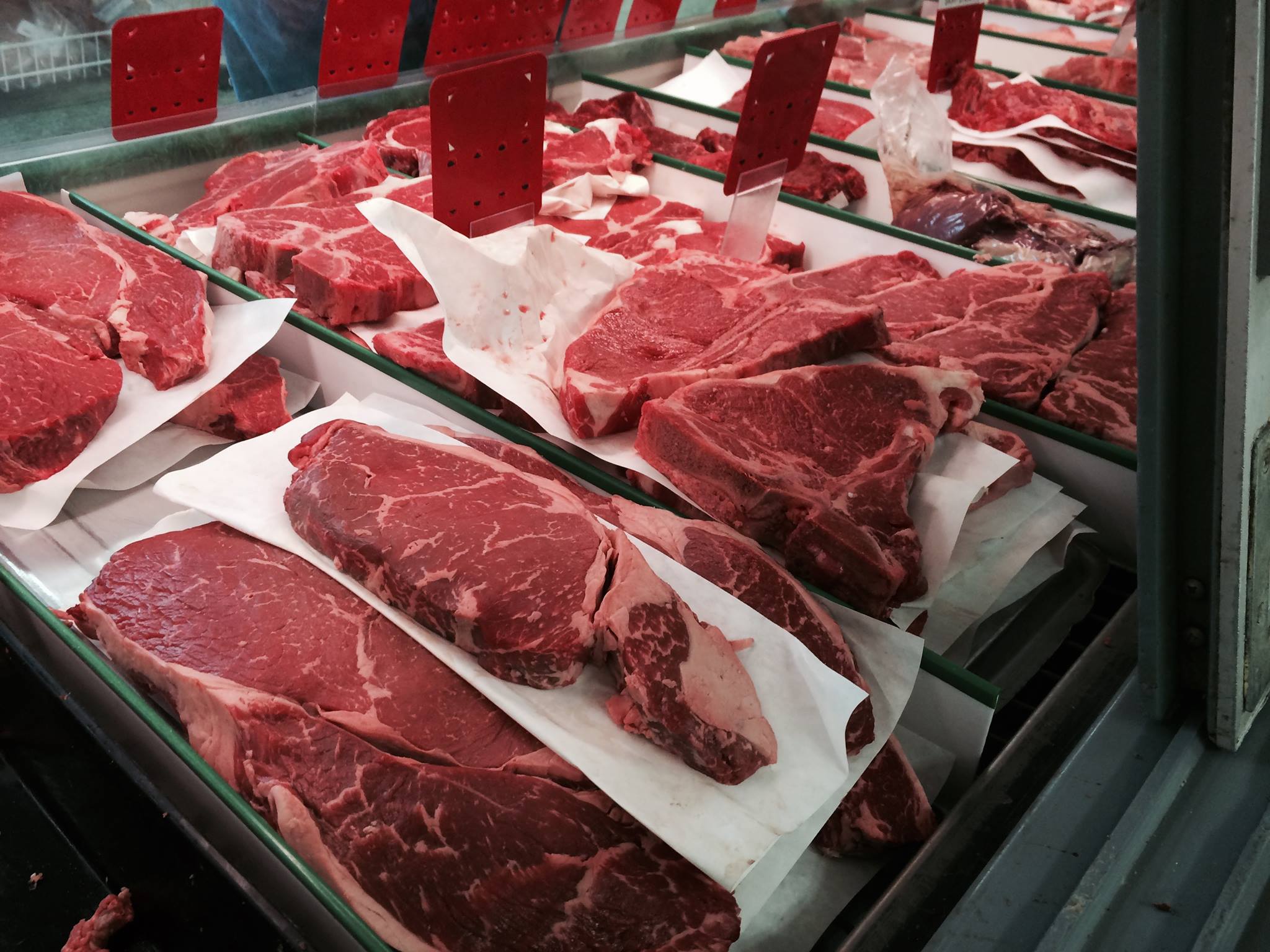 An array of raw steaks in the Ready Meat's case, each marbled with pink fat and separated by a piece of butcher paper 