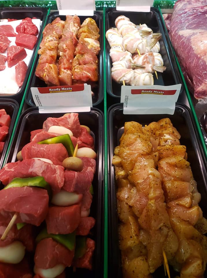 Brightly-colored kabob meat on skewers, pre-seasoned and in containers.